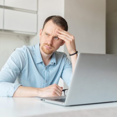 Worried,Young,Man,Using,Laptop,Computer,For,Looking,For,The
