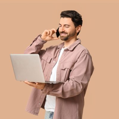 Young,Man,With,Laptop,Talking,By,Modern,Mobile,Phone,On